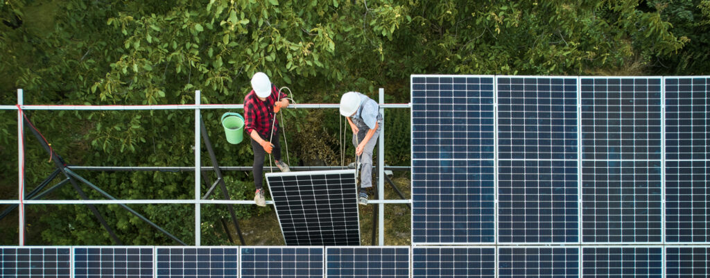 Two contractors installing a group of solar panels.