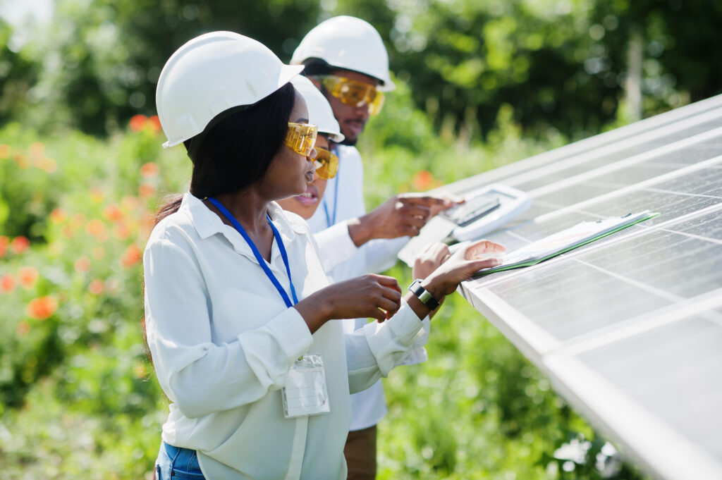 Three contractors installing a solar panel in a field.